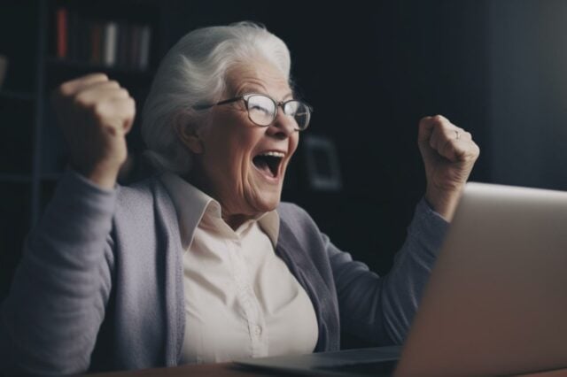 Une personne âgée qui se réjouit devant son ordinateur