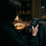 Personne regardant un smartphone en mode navigation privée, écran flou, ambiance tamisée, anonymat suggéré sans contenu explicite.