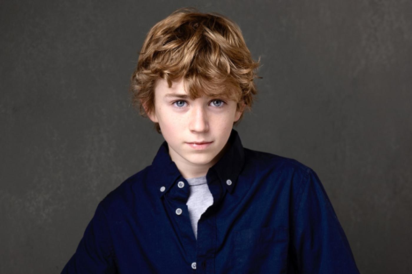 Photo du jeune nouvel acteur incarnant Percy Jackson à l'écran. Il a des yeux bleu/vert et des cheveux blonds ébouriffés