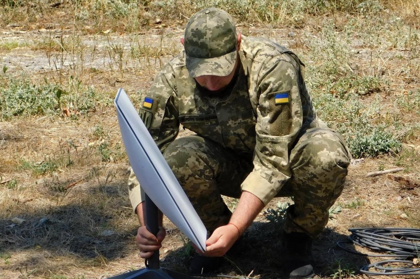 Un soldat ukrainien en train d'installer un terminal satellite web Starlink